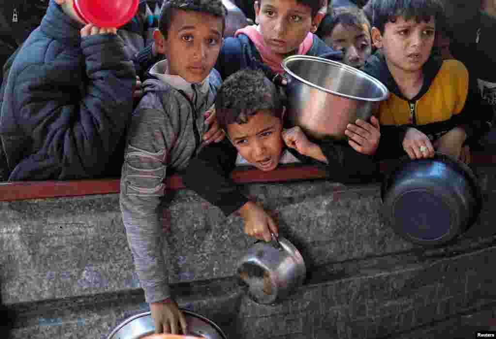 Palestinian children wait to receive food cooked by a charity kitchen amid shortages of food supplies in Rafah, in the southern Gaza Strip as the ongoing conflict between Israel and the Palestinian Islamist group Hamas continues. REUTERS/Ibraheem Abu Mustafa