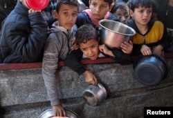 FILE - Palestinian children wait to receive food cooked by a charity kitchen amid shortages of food supplies in Rafah, in the southern Gaza Strip, February 5, 2024.