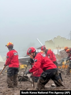 In this photo provided by South Korea National Fire Agency, rescue workers search for people at the site of a landslide caused by heavy rain in Yecheon, July 16, 2023.