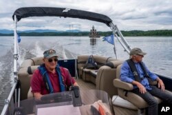 Van Calhoun and Tony Mafeo, volunteers for the Hudson-Athens Lighthouse Preservation Society, pilot a boat away from the lighthouse, June 12, 2024, in Hudson, New York.