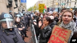 Police in riot gear stand guard as demonstrators chant slogans outside the Columbia University campus, April 18, 2024, in New York.