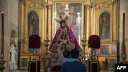FILE - A father and his son look at a figure of Jesus Christ at San Esteban church, in Seville, Spain, on March 30, 2021. 