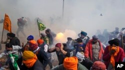 Protesting farmers run away from exploding tear gas shells used by the police near Shambhu border, which divides northern Punjab and Haryana states, some 200 kilometers (120 miles) from New Delhi, India.