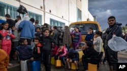 FILE - Palestinians displaced by the Israeli bombardment of the Gaza Strip queue for water at a U.N. displacement camp in the southern town of Khan Younis, Gaza Strip, November 19, 2023.