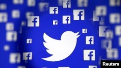 FILE - Logo of the Twitter and Facebook are seen through magnifier on display in this illustration taken in Sarajevo, Bosnia and Herzegovina, December 16, 2015.