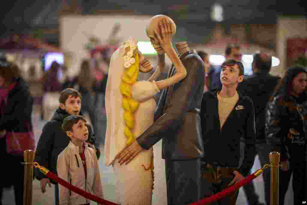 People look at a skeleton couple kissing installation dubbed " 'Till Death Do Us Part" during a Valentine's Day event in Bucharest, Romania, Feb. 13, 2024.