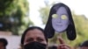 Una mujer sostiene un recorte de papel con una máscara con el rostro de Rocío San Miguel, durante una manifestación frente a la embajada de España para exigir su liberación. Caracas, 20 de febrero 2024