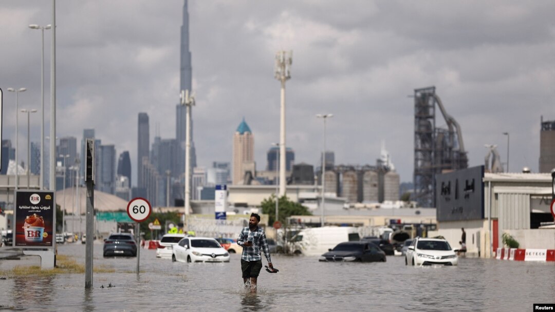 Seseorang berjalan di genangan banjir akibat hujan lebat, dengan latar belakang menara Burj Khalifa di Dubai, Uni Emirat Arab, 17 April 2024. (REUTERS/Amr Alfiky)