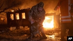 Firefighters rescue a dog as they extinguish a fire following a Russian attack on a residential neighborhood in Kharkiv, Ukraine, Feb. 10, 2024.