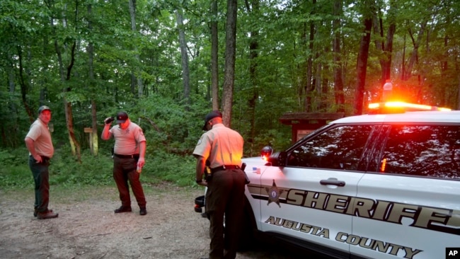 Las autoridades vigila la entrada a Mine Bank Trail, un punto de acceso a la operación de rescate a lo largo de Blue Ridge Parkway donde un Cessna Citation se estrelló sobre un terreno montañoso cerca de Montebello, Virginia, el domingo 4 de junio de 2023. (Randall K. Wolf vía AP)