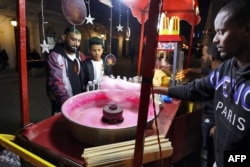 Seorang pria membeli permen kapas untuk putranya, di sebuah kawasan hiburan di Tripoli, pada hari pertama bulan suci Ramadan, 23 Maret 2023. (Mahmud Turkia/AFP)