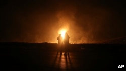 Two men look at flames after a natural gas pipeline exploded outside the city of Boroujen in the western Chaharmahal and Bakhtiari province, Iran, Feb. 14, 2024. 