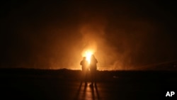 FILE - Two men look at flames after a natural gas pipeline exploded outside the city of Boroujen in the western Chaharmahal and Bakhtiari province, Iran, Feb. 14, 2024. (Reza Kamali Dehkordi/Fars News Agency via AP)