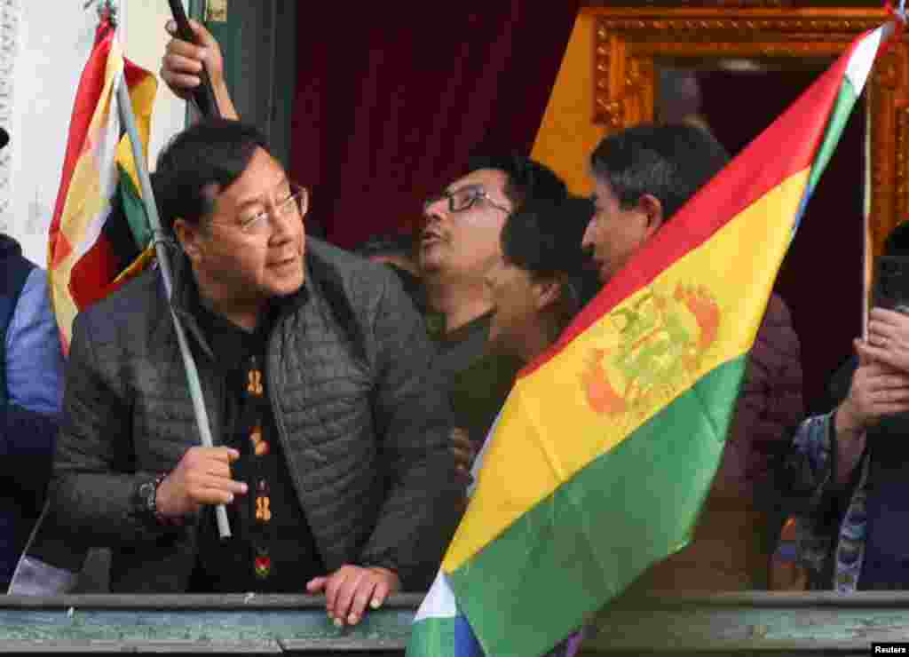 Bolivia&#39;s President Luis Arce holds a flag as he stands on a balcony after he &quot;denounced the irregular mobilization&quot; of some units of the country&#39;s army in La Paz, June 26, 2024.
