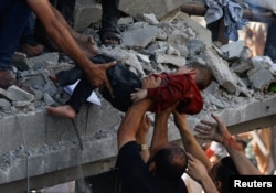 Palestinians carry a child casualty at the site of an Israeli strike on a house, in Khan Younis, in the southern Gaza Strip, October 24, 2023.