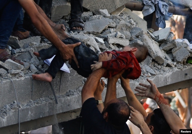 Palestinians carry a child casualty at the site of an Israeli strike on a house, in Khan Younis, in the southern Gaza Strip, October 24, 2023.