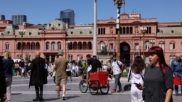 Ciudadanos pasean frente a la sede del Poder Ejecutivo, la Casa Rosada, en Buenos Aires, a escasas horas para la toma de posesión de Javier Milei.