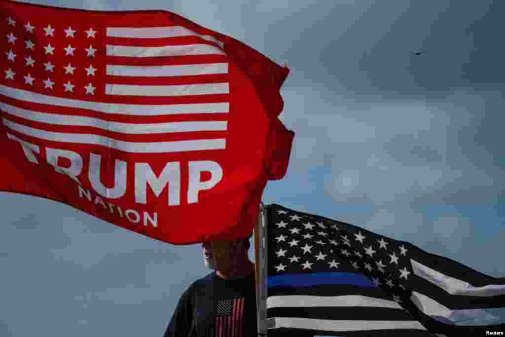 .Поддржувач на поранешниот американски претседател Доналд Трамп држи знаме за спроведување на законот пред неговото одморалиште Мар-а-Лаго.