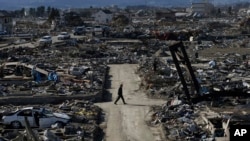  In this March 27, 2011 file photo, a man walks through an earthquake destroyed neighborhood below Weather Hill in Natori, Japan. (AP Photo/Wally Santana, File)