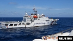 资料照片：2024年2月8日，菲律宾南中国海的斯卡伯勒浅滩（中国称黄岩岛）附近，一艘中国海警船从菲律宾海警船“特雷莎·马格巴努亚号”旁驶过。（路透社照片）