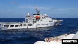 资料照：2024年2月8日，菲律宾南中国海斯卡伯勒浅滩附近，一艘中国海岸警卫队船只在菲律宾海岸警卫队船只特雷莎·马格巴努亚号旁驶过。（路透社）