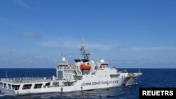 资料照：2024年2月8日，菲律宾南中国海斯卡伯勒浅滩附近，一艘中国海岸警卫队船只在菲律宾海岸警卫队船只特雷莎·马格巴努亚号旁驶过。（路透社）