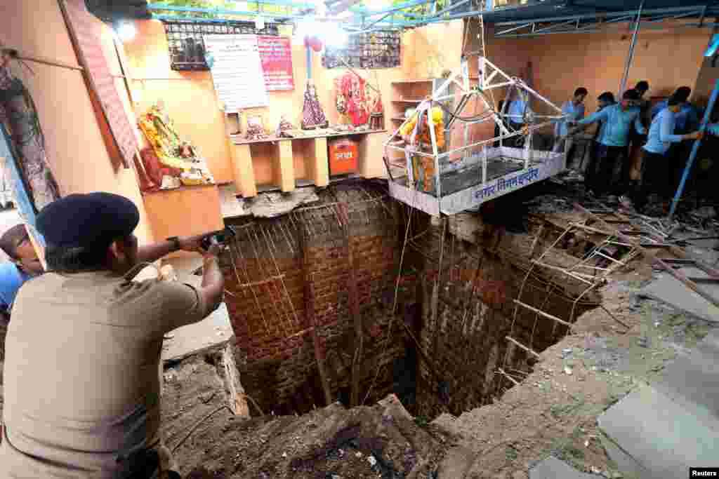 A police officer uses his mobile phone to take pictures during rescue operation after the roof of a stepwell in a temple complex collapsed in the central city of Indore, India.