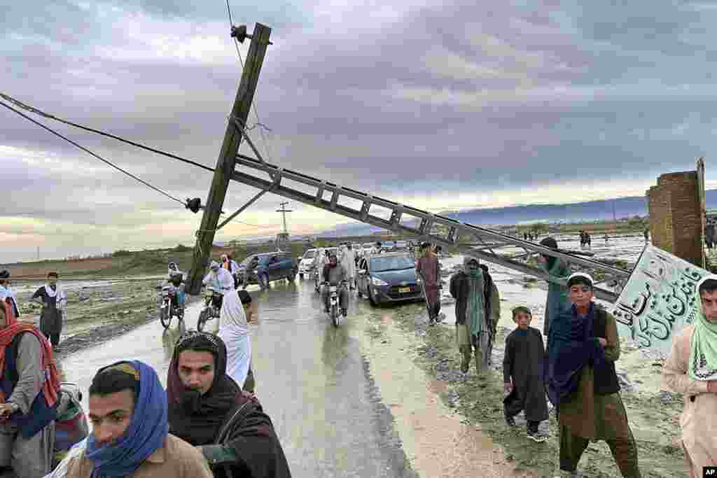 Луѓе поминуваат покрај паднат електричен столб по поплави предизвикани од обилните дождови во близина на областа Чаман, Пакистан. Громовите и обилните дождови доведоа до 14 смртни случаи во Пакистан, соопштија властите, со што бројот на загинати од четиридневните екстремни временски услови се искачи на најмалку 63.