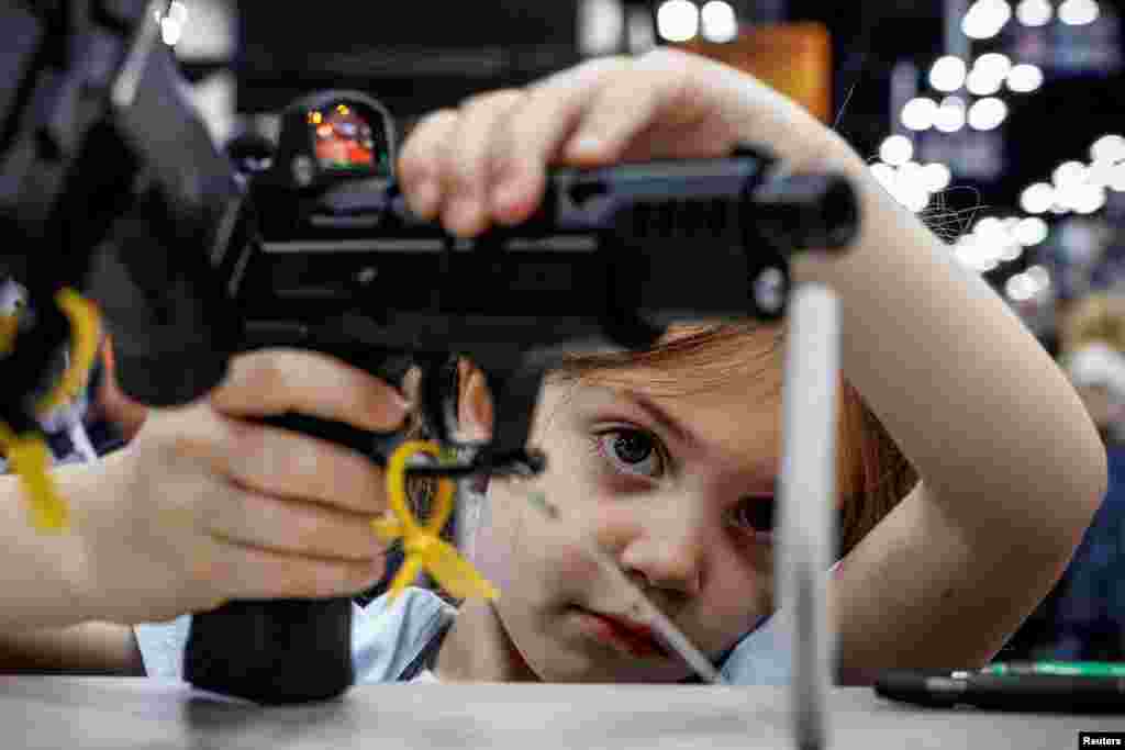 A child holds a gun at the National Rifle Association (NRA) annual convention in Indianapolis, Indiana, April 15, 2023. 