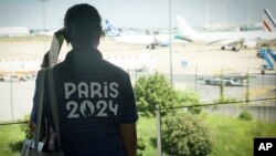 A Paris Olympics volunteer watches planes on the tarmac at Charles de Gaulle airport, July 19, 2024 in Roissy, north of Paris.