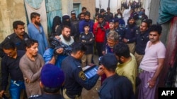 FILE - Police personnel test biometrics of Afghan refugees during a search operation to identify alleged illegal immigrants, on the outskirts of Karachi, Pakistan, Nov. 17, 2023.