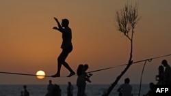 A man balances in silhouette against the setting sun on a beach in the Israeli coastal city of Tel Aviv on April 19, 2024.
