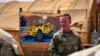 FILE - Major General Kenneth Ekman speaks in front of a "Welcome to Niamey" sign depicting U.S. military vehicles at Air Base 101 in Niger, May 30, 2024. (U.S. Air Force via AP)