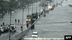 Para penumpang melewati jalan yang terendam banjir akibat hujan lebat di Chennai, 4 Desember 2023. Topan Michuang diperkirakan akan menghantam pantai selatan India pada 5 Desember (R. Satish BABU / AFP)