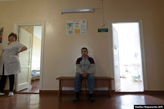 Oleksandr, a patient, sits in a corridor at a psychiatric hospital In Kramatorsk, Ukraine, Tuesday March 21, 2023. (AP Photo/Vasilisa Stepanenko)