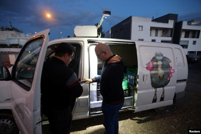 A man buys products outside Pantelis Panteli's van in Nicosia, Cyprus February 1, 2024. (REUTERS/Yiannis Kourtoglou)