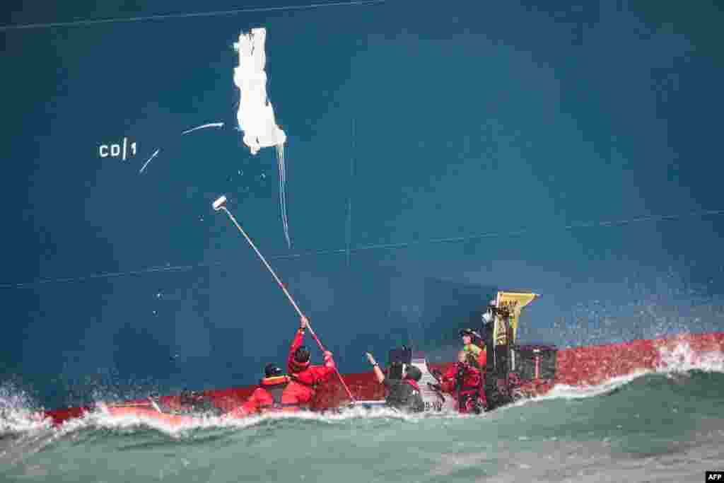 Greenpeace France activists paint the words &#39;Gas Kills&#39; on the side of the TotalEnergies Cape Ann LNG terminal, anchored off the northern French port city of Le Havre, in the English Channel. (Photo by LOU BENOIST / AFP)