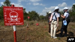 FILE - Ukraine deminers talk to a Cambodian deminer near a warning sign during a technical training session on demining technologies in Battambang province on Jan. 19, 2023.