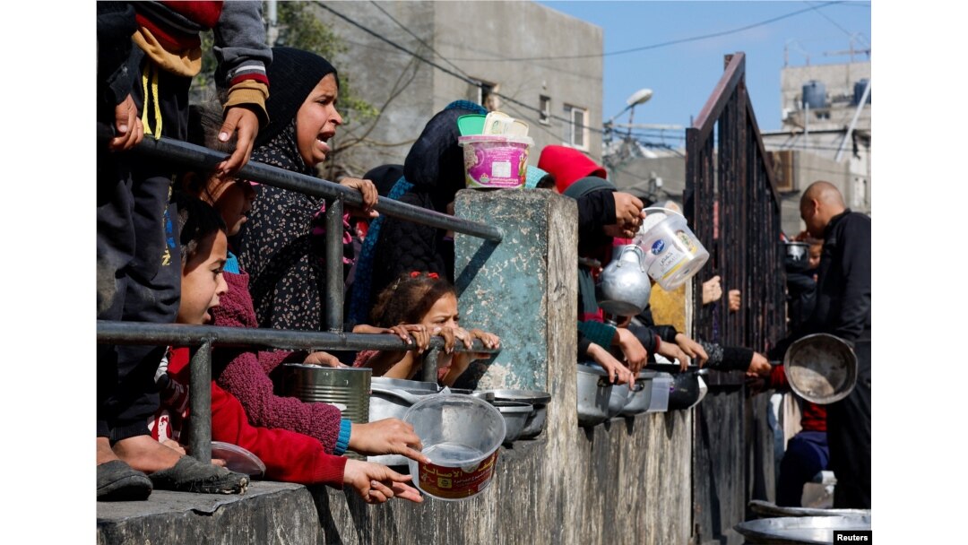 Palestinian children wait to receive food cooked by a charity kitchen amid shortages of food supplies, as the ongoing conflict between Israel and the Palestinian Islamist group Hamas continues, in Rafah, in the southern Gaza Strip, Feb. 20, 2024.