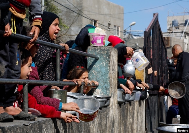 Palestinian children wait to receive food cooked by a charity kitchen amid shortages of food supplies, as the ongoing conflict between Israel and the Palestinian Islamist group Hamas continues, in Rafah, in the southern Gaza Strip, Feb. 20, 2024.