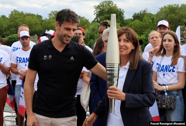 President of the Paris 2024 Games, Tony Estanguet with Paris Mayor Anne Hidalgo Carry the Olympic Torch during the torch parade in Paris, France on July 25, 2023. (REUTERS/Pascal Rossignol)