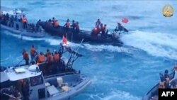 Personel Garda Pantai China menaiki perahu karet berlambung kaku (berwarna hitam) selama konfrontasi dengan personel Angkatan Laut Filipina di kapal masing-masing (berwarna abu-abu) di dekat Second Thomas Shoal di Laut China Selatan. (Foto: AFP)