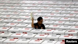Seorang pekerja membawa bahan pemilihan saat menyiapkan kotak suara sebelum didistribusikan ke TPS di sebuah gudang di Jakarta, 15 April 2019. KPU memulai tahapan pendaftaran bakal calon anggota legislatif pada Pemilu 2024.(Foto: REUTERS/Willy Kurniawan)