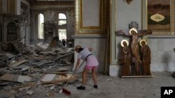 A woman helps clean up inside the Spaso-Preobrazhensky (Lord's Transfiguration) Cathedral after it was heavily damaged in Russian missile attacks in Odesa, Ukraine, July 23, 2023.