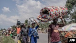 Des personnes transportent certaines de leurs affaires alors qu'elles fuient le territoire de Masisi à la suite d'affrontements entre les rebelles du M23 et les forces gouvernementales, sur une route près de Sake, le 7 février 2024.