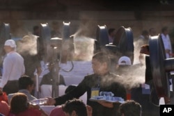 FILE - Seorang pekerja membagikan botol air kepada tamu yang duduk di dekat pendingin untuk menangkal panas pada upacara pelantikan Narendra Modi sebagai perdana menteri India di istana kepresidenan India di New Delhi, India, 9 Juni 2024. (AP/Manish Swarup)