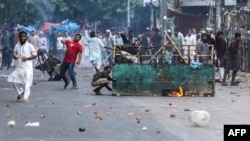 Protesters pelt stones as they clash with police during the ongoing anti-quota protest in Dhaka on July 19, 2024.