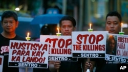 FILE - Para pengunjuk rasa memegang plakat sambil menyalakan lilin dalam protes menentang "pembunuhan di luar hukum" terhadap kampanye "Perang Antinarkoba" oleh Presiden Rodrigo Duterte di pinggiran kota Quezon, timur laut Manila, Filipina 8 Oktober 2016 (foto: dok). 