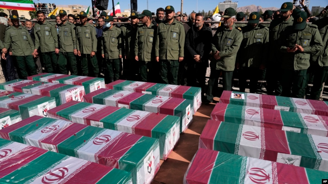 FILE - Revolutionary Guard members stand over the flag-draped coffins of victims a bomb explosion during their funeral ceremony in the city of Kerman, Iran, Jan. 5, 2024. The Iranian government linked the attack to ethnic-Tajik fighters of the Islamic State Khorasan Province.