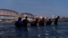 FILE — Migrants link arms with each other as they wade into the Rio Grande River with intentions to cross into Eagle Pass, Texas, U.S., in Piedras Negras, Coahuila, Mexico, Feb. 24, 2024. 